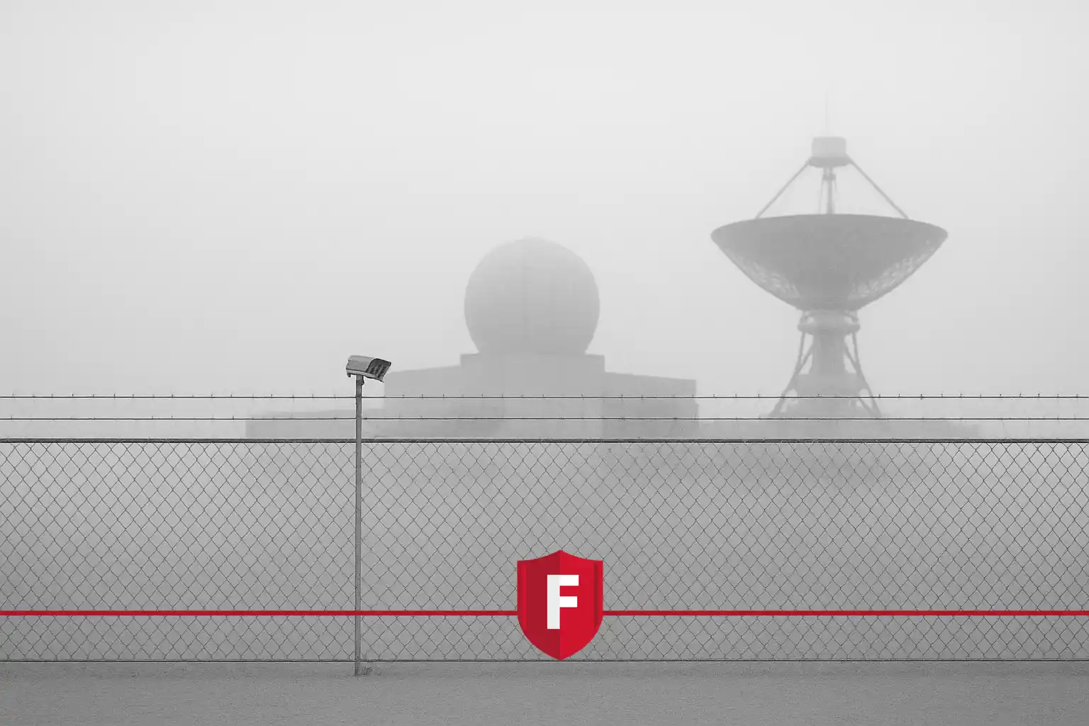 A secured perimeter fence with radar and satellite installations in fog, protected by FOTAS fiber optic sensing system.
